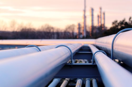 Kiwa inspected Pipelines leading to an industrial plant at sunset, highlighting the infrastructure of the oil and gas industry