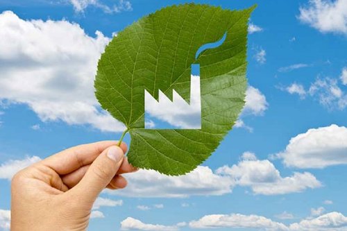 leaf with a cut out depiction of a factory with a smokey chimney, being help up to the sky