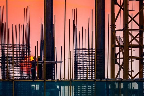 Steel building site with builders and sunset