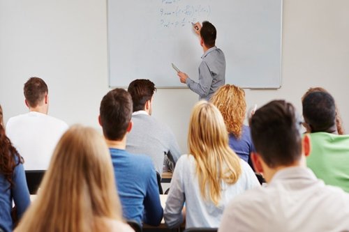 College classroom with students listening to a male Kiwa trainer writing equations on a whiteboard