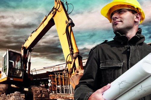 Construction site with excavator and confident worker in hard hat and holding blueprints, cloudy sky background