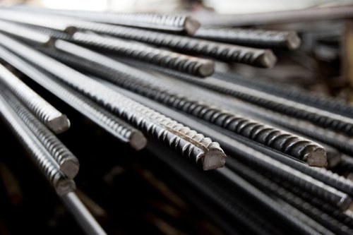 Stapel metalen wapeningsstaven met ribbels, liggend en geordend.