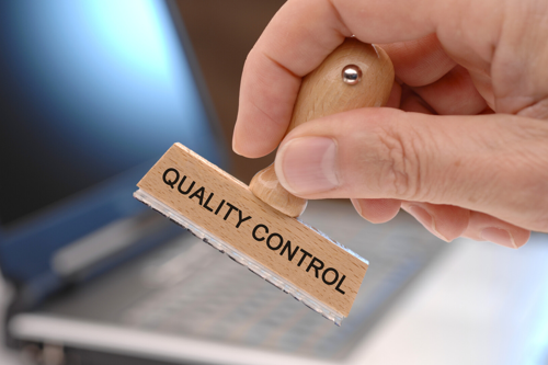Een hand houdt een stempel met de tekst "QUALITY CONTROL"