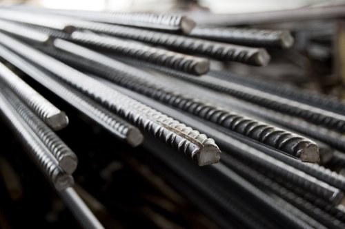 Stapel metalen wapeningsstaven met ribbels, liggend en geordend.