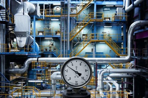 Industriell anläggning med stora rör, metalltrappor och en tryckmätare i förgrunden i en bild som förmedlar att Kiwa arranger branschseminariet Kraftvärmedagarna hösten 2026.