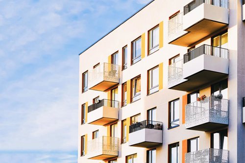 Flerfamiljshus med vita fasader och många balkonger mot blå himmel i en bild som förmedlar ett objekt, bostadshus, som alltid är aktuellt för certifierade radonkonsulter. .