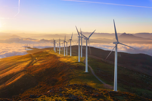 wind trubines on top of a hill during the sunset