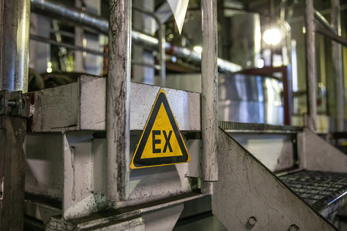 Industriell miljö med metallstegar och ett varningsmärke med texten "EX".