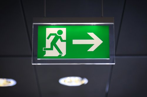 Groen nooduitgangbord, hangend aan een plafond.