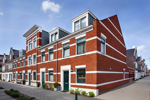 Rij moderne rode bakstenen huizen met witte accenten onder een blauwe lucht.