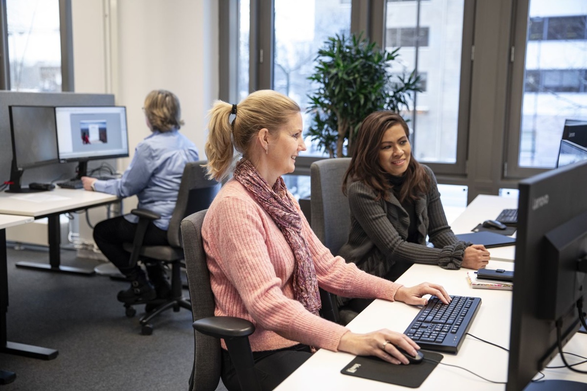 Drie vrouwen werken achter computers in een modern kantoor