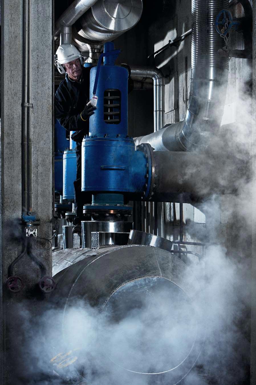 Industriell röranläggning med stora blå ventiler, metallrör och ånga i ett maskinrum - Kiwa håller i en kurs gällande FEM-analys av tryckkärl.
