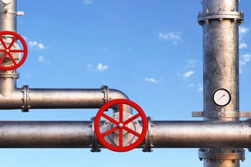 Industriella metallrör med röda ventilhjul och tryckmätare mot blå himmel - Kiwa håller i kursen: Rörledningar, EN 13480.