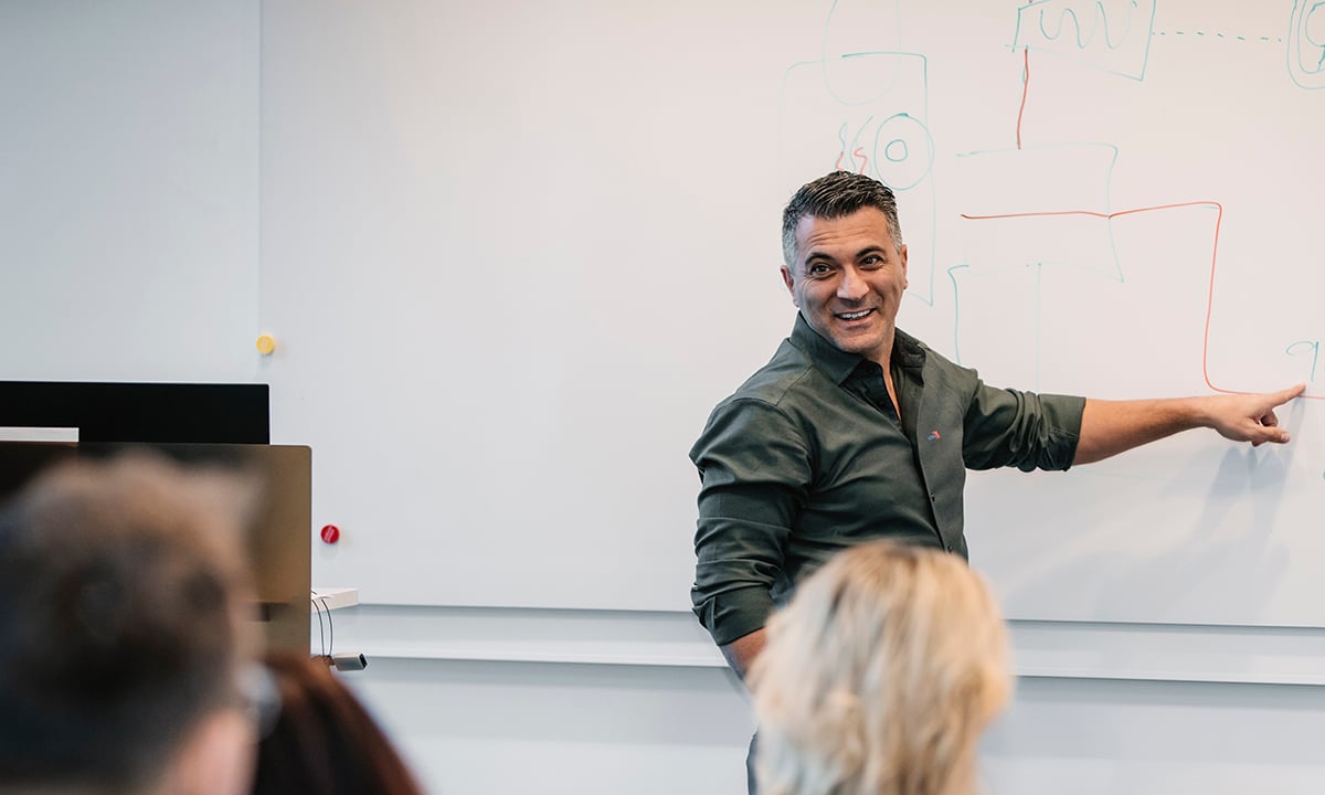 Kiwa trainer in a classroom giving a presentation on a whiteboard with an audience observing.